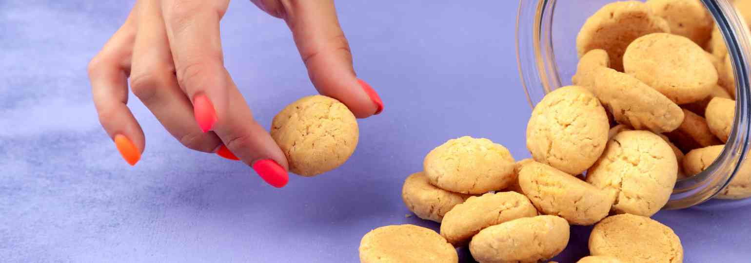 female-hand-takes-cookie-from-scattered-pile-from-transparent-glass-bank (3)@@.jpg